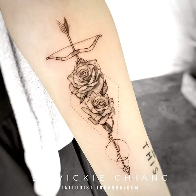 A rose arrow tattoo with stunning details by @earthaltarstudio