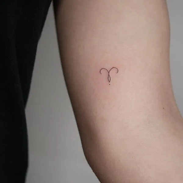 A minimalist Aries astrology symbol tattoo by @annaleatattoo