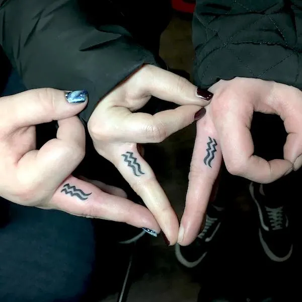 Matching Aquarius symbol finger tattoos by @tyrallane