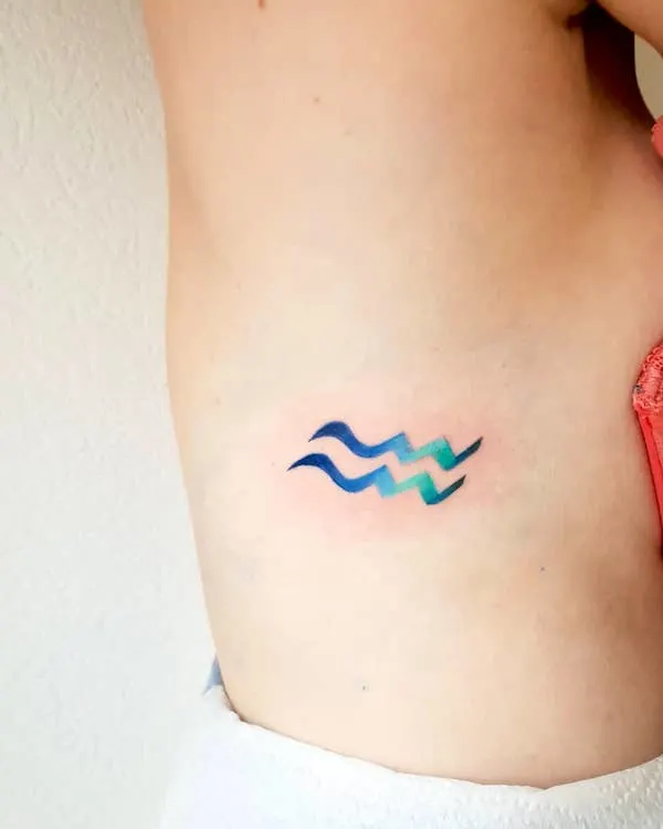 A rib tattoo of the Water-bearer symbol by @cora_linez