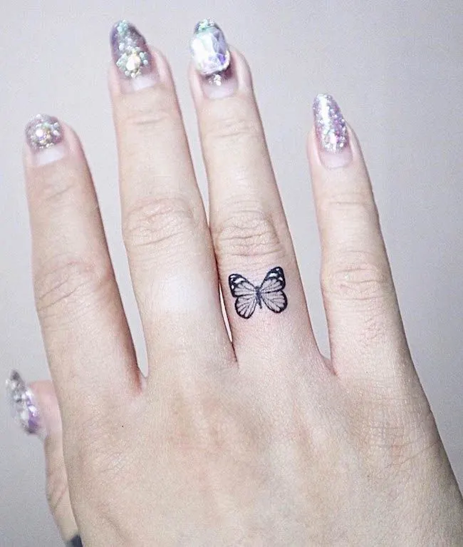 A small butterfly ring finger tattoo for women by @j.ryong_tattoo- Dainty finger tattoo ideas