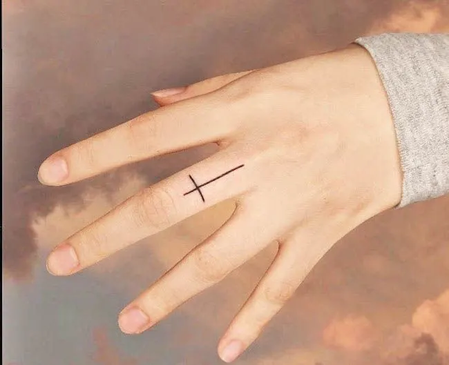 A cross tattoo on the middle finger by @pomme_tat- Dainty finger tattoo ideas