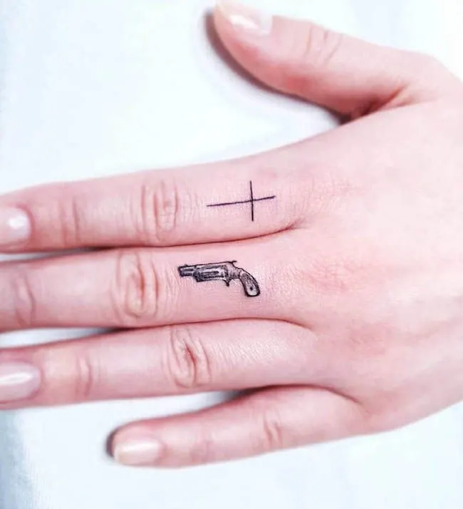 A fierce gun tattoo by @subc_tattooer - Bold statement finger tattoos