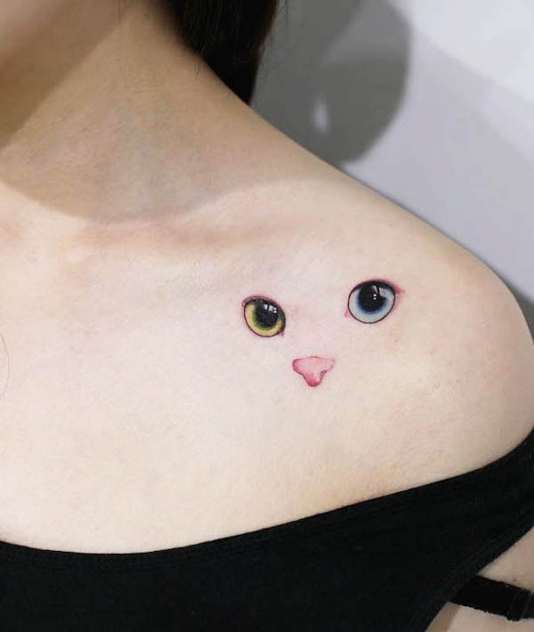 A cute cat face tattoo on the shoulder by @tattooist_doy - Minimalist tattoos for cat lovers