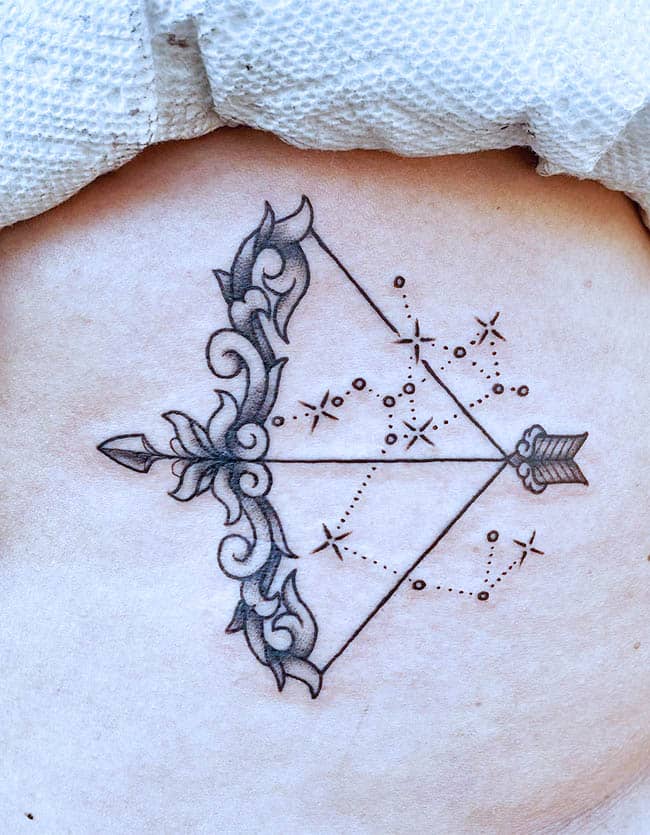 A sparkling bow and arrow tattoo by @gracietattoos