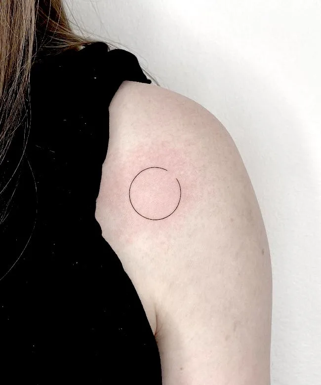 Line art circle tattoo on the inner arm.