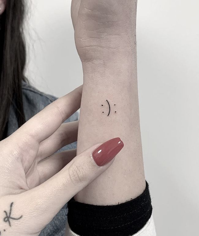 Smiley face on finger tattoo