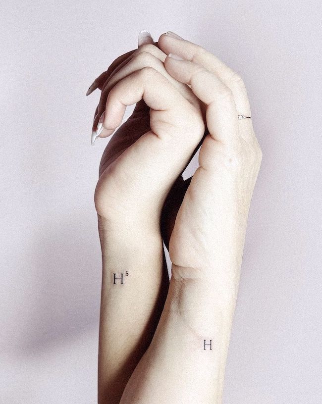 Matching initials tattoos on the wrist by @featherandmink