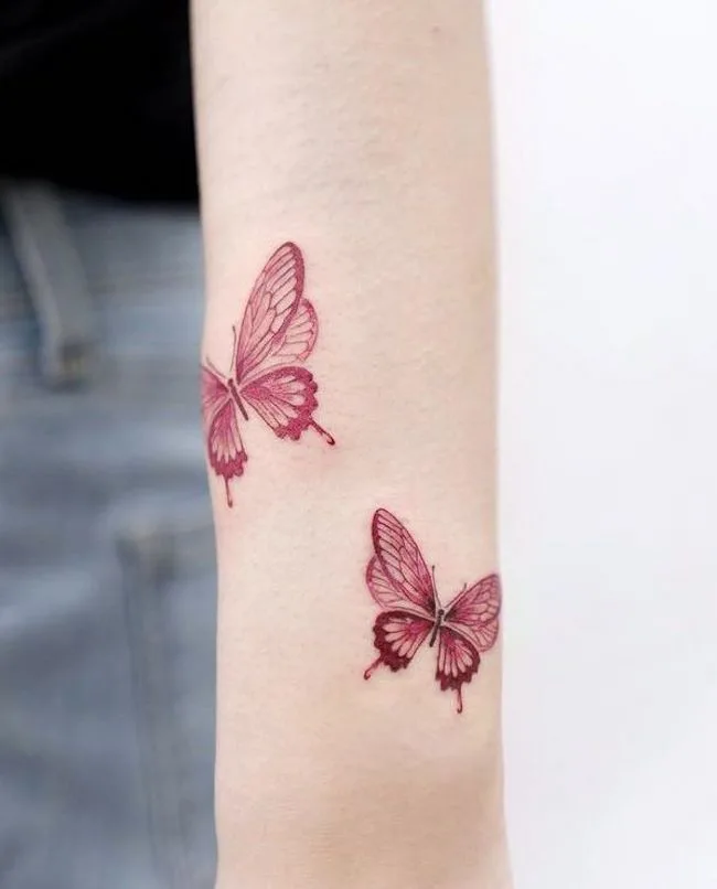 Fine line red butterfly tattoo on the shoulder blade