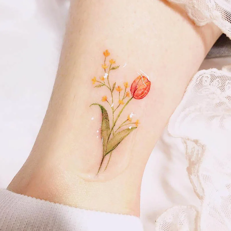 Yellow tulip and mistflower ankle tattoo by @rostattoo2