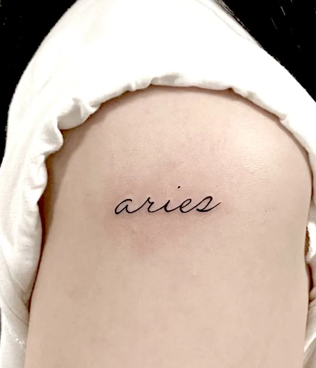 Aries script shoulder tattoo by @dda_ttoo