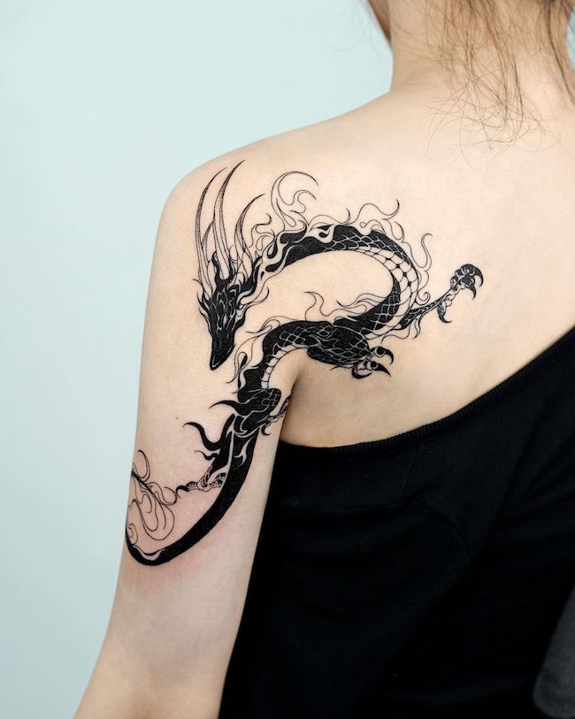 Empowering black dragon shoulder tattoo by @bium_tattoo - Classy black and white shoulder tattoos for women