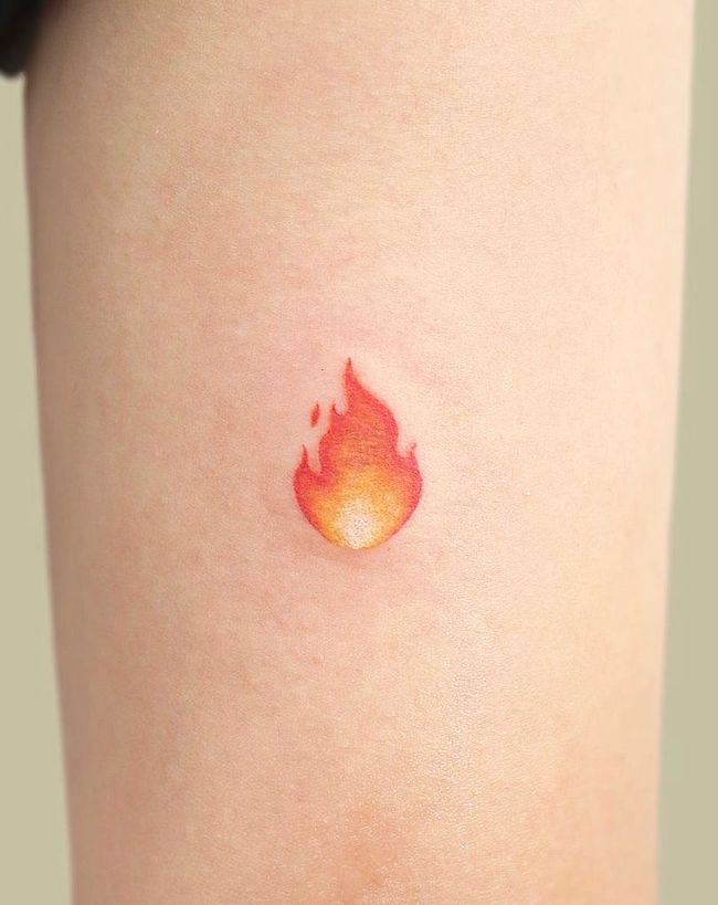 Tiny flame tattoo done on the inner arm using red ink