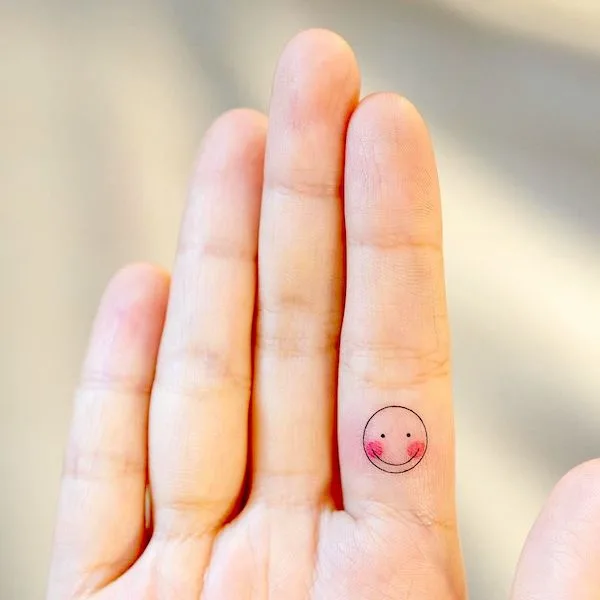 Small smiley face on index finger by @tattooist_arar