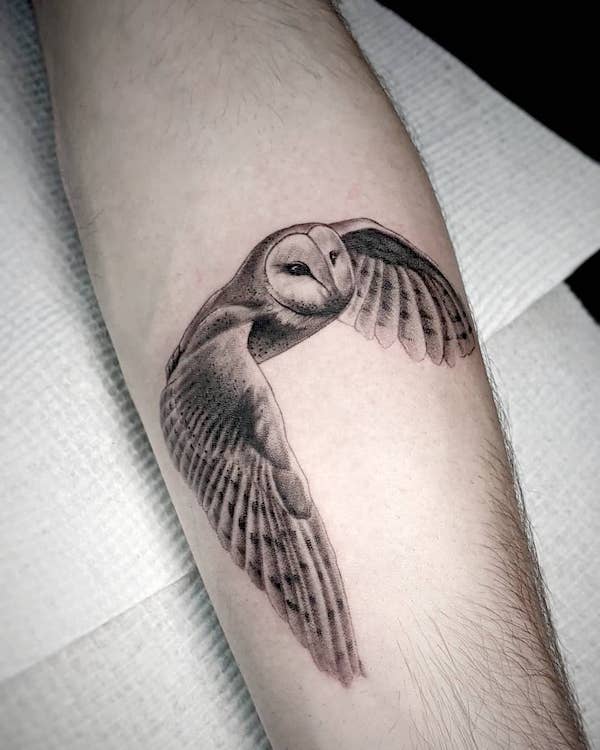 Flying barn owl tattoo on the left shoulder blade