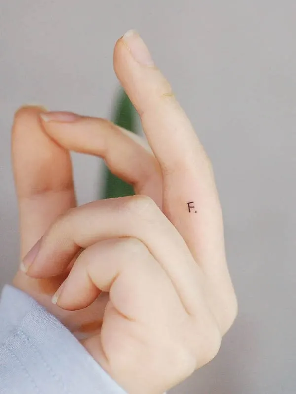 A tiny F finger tattoo by @wittybutton_tattoo