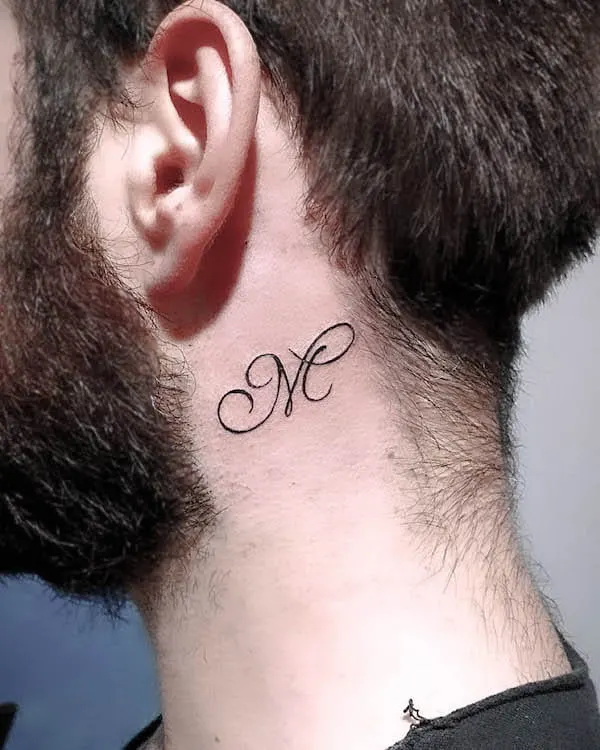 Behind the ear M initial tattoo by @mrktattoozone