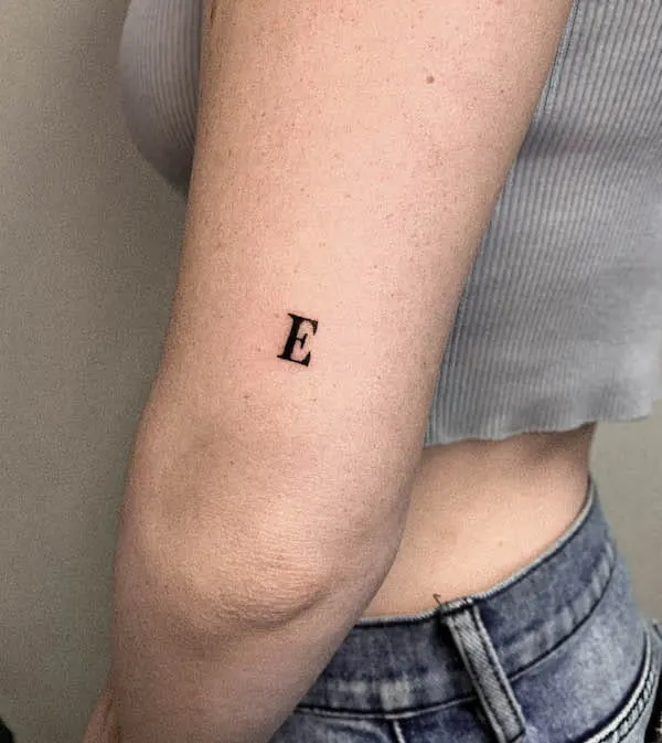 Small E initial elbow tattoo by @cococreativetattoo