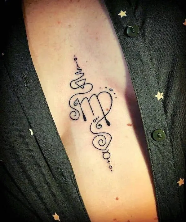 An abstract Virgo tattoo between the boobs