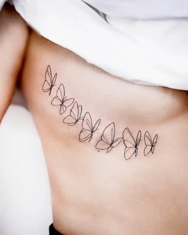 Fine line butterflies tattooed on the rib