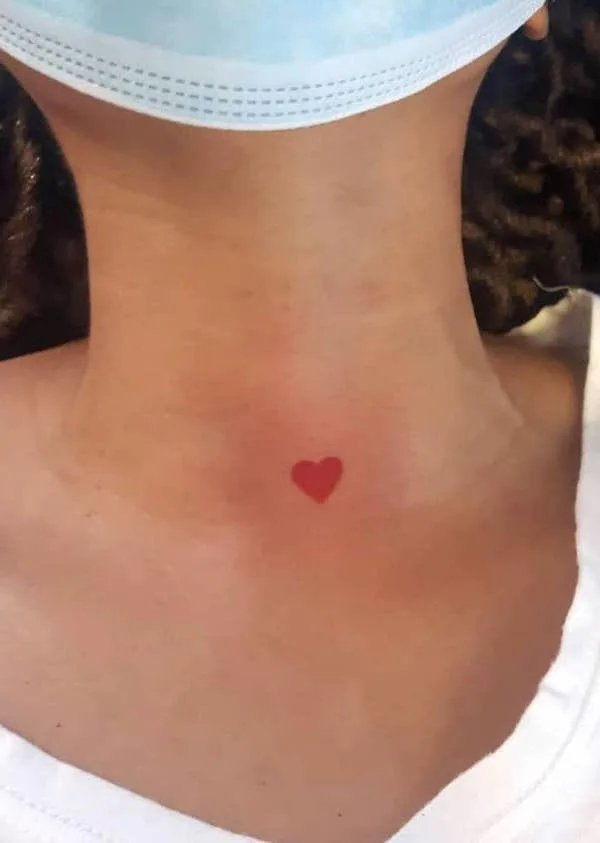 Tiny red heart throat tattoo by @wonnietattoos