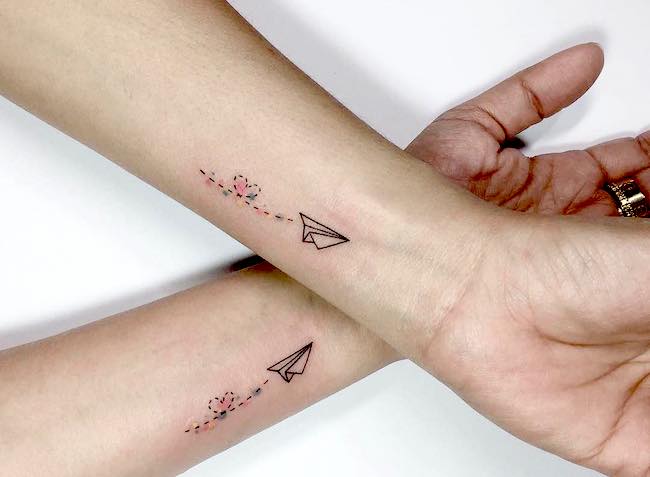 Hearty paper plane matching wrist tattoos by @playground_tat2