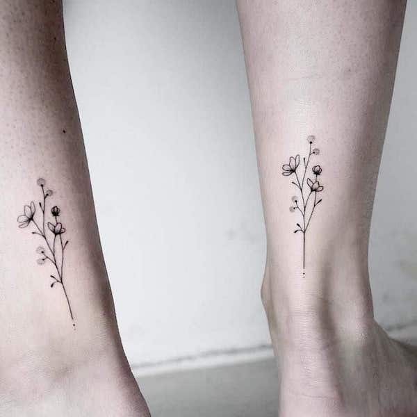 Matching feminine floral tattoos above the ankle by @reh.ink