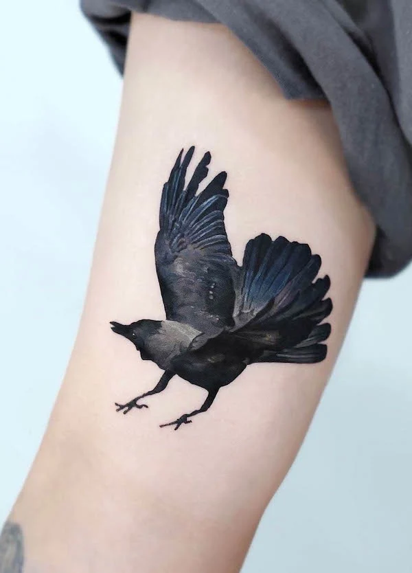 A flying crow bicep tattoo by @stuffie.ink_