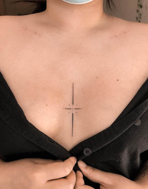 Simple cross and star tattoo between boobs by @shellaeves.art