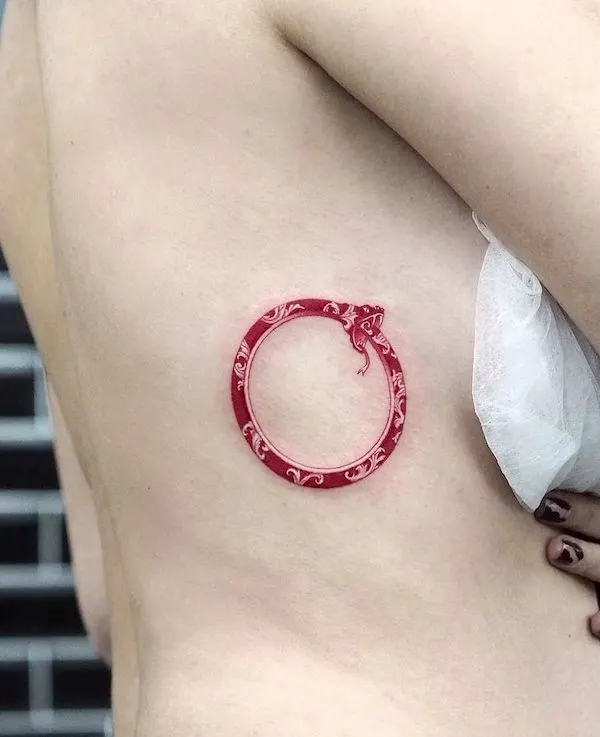 Red oriental ouroboros rib tattoo by @ozgedemirart