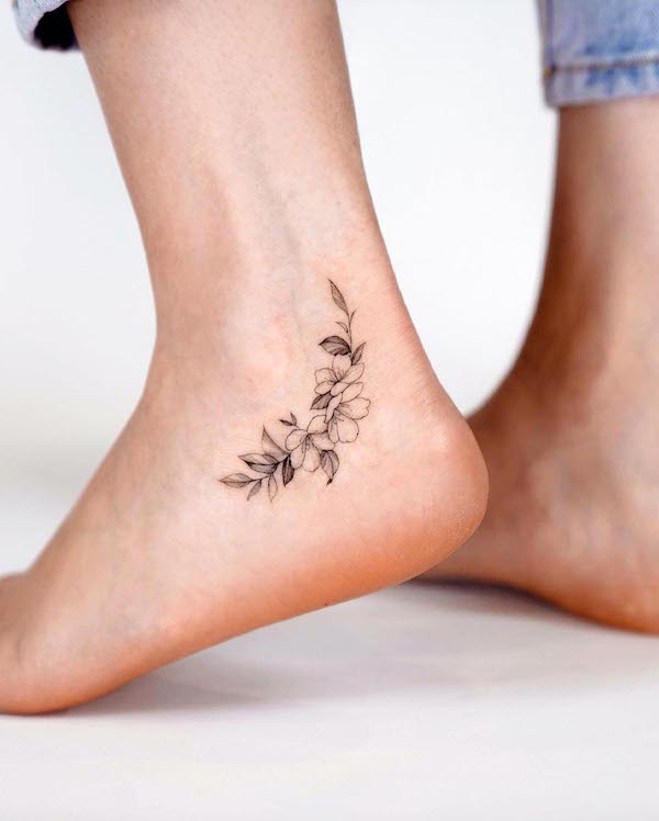 Delicato tatuaggio a fiori sulla caviglia di @zeetattoo