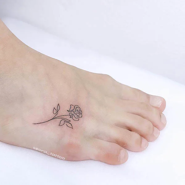 Small rose outline foot tattoo by @seora_tattoo