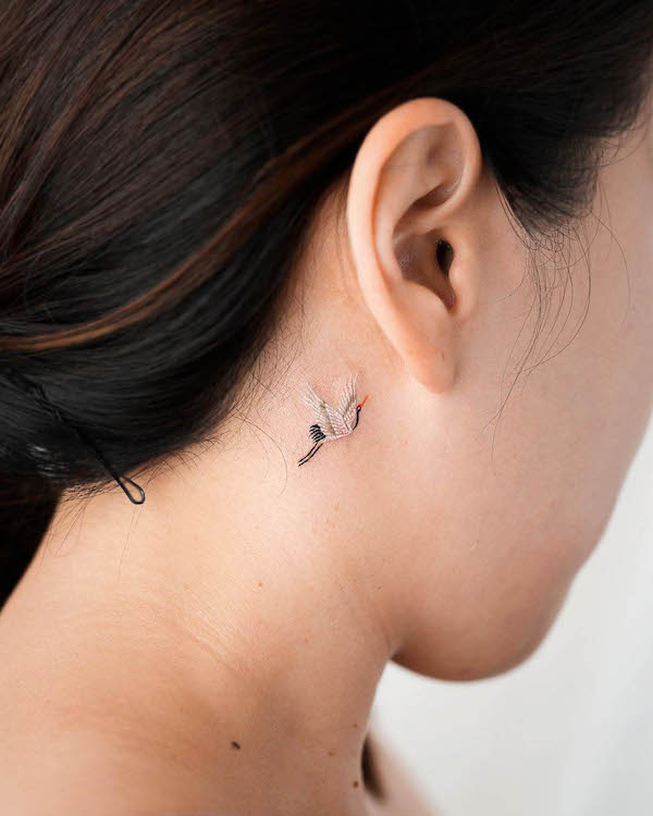 Small crane behind-the-ear tattoo by @tattooist_eq