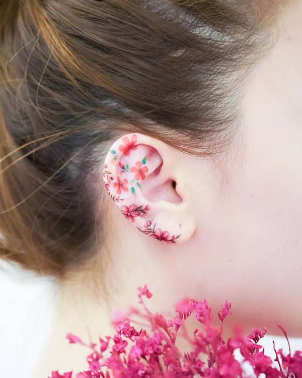 Vibrant flower ear tattoo by @mini_tattooer