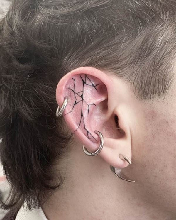 Cracks on the ear tattoo by @rhi.draws