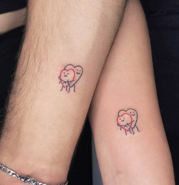 Hugging heart matching tattoos by @tattooss.alkaya